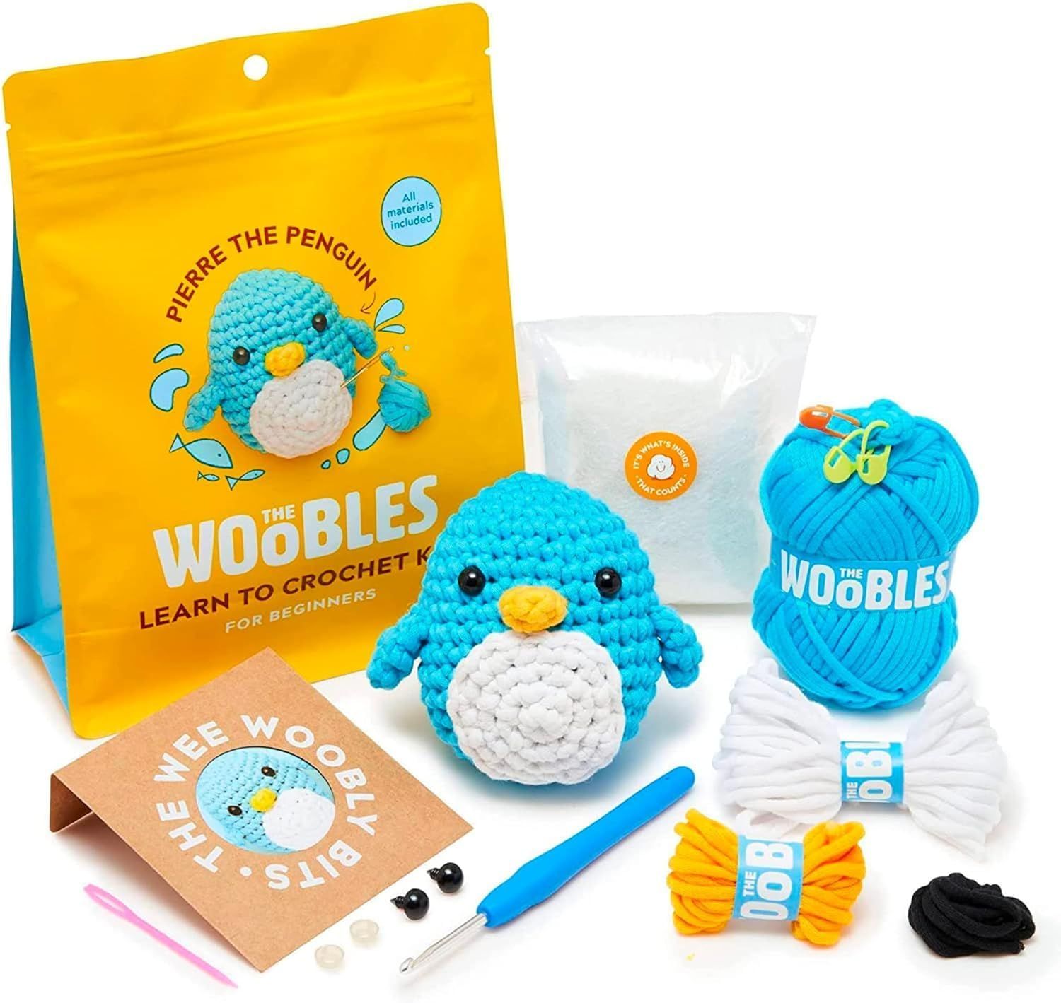 Shows buyers exactly what they will receive in the crochet kit, including the finished penguin example, yarn, tools, instruction booklet, and all necessary materials to complete the project.