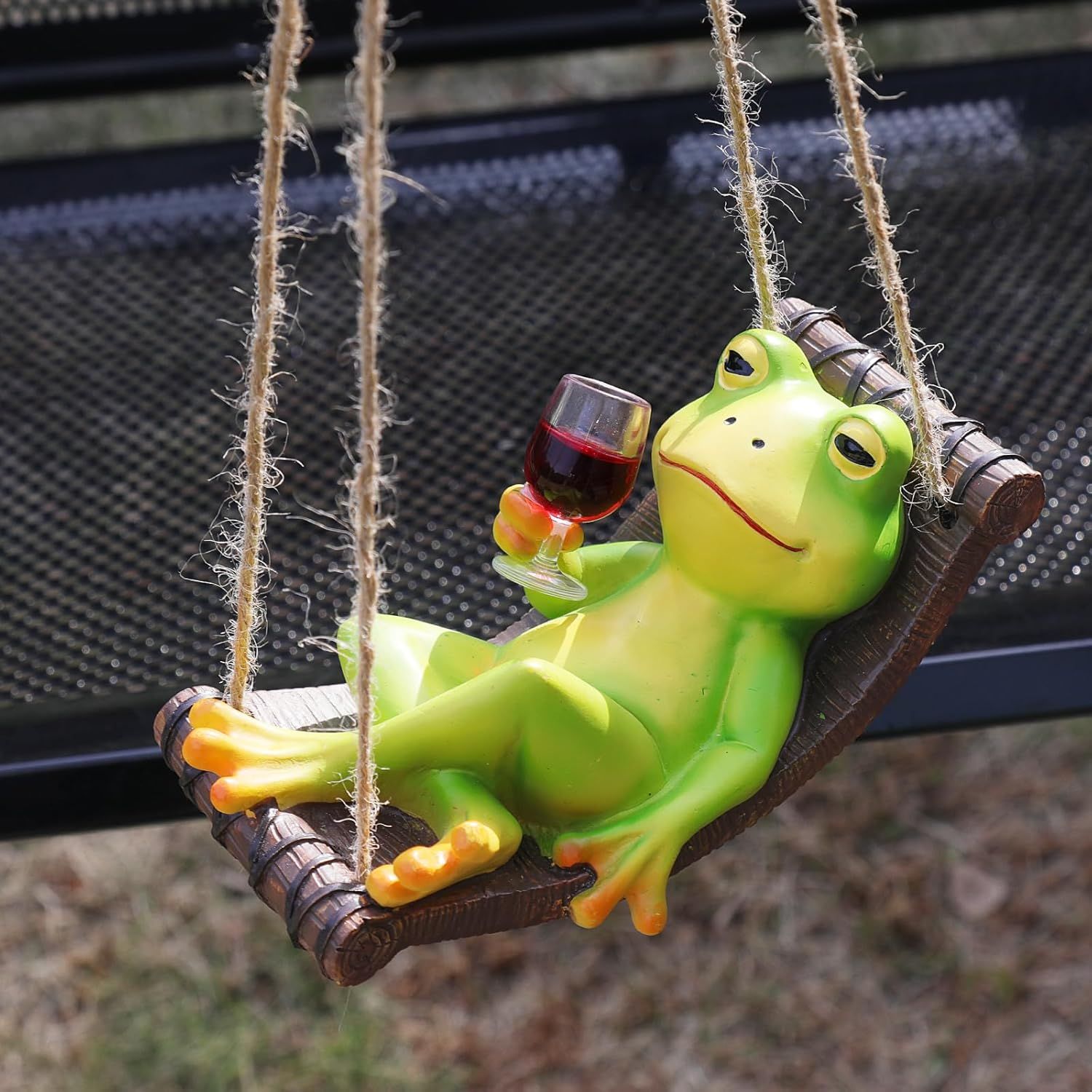 Shows the core product—a decorative frog figurine on a swing holding a wine glass—to communicate its whimsical, relaxing character and appeal as a garden or outdoor decoration. Displays the product…