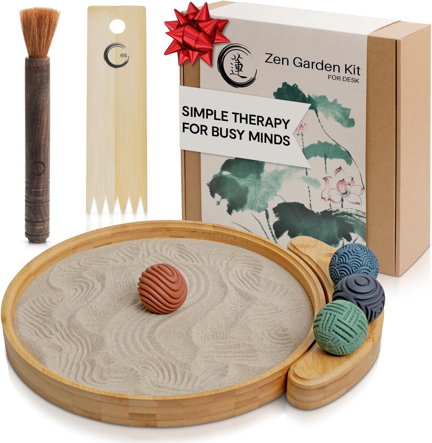 Displays the complete zen garden kit including the sand tray, decorative balls, brush, and rake to show shoppers everything included in the purchase. Shows the retail packaging with gift bow to…