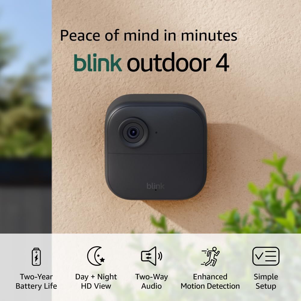 Shows the Blink Outdoor 4 camera mounted on an exterior wall in a real outdoor setting to demonstrate its intended use case and help shoppers visualize how it would look installed at their home.…