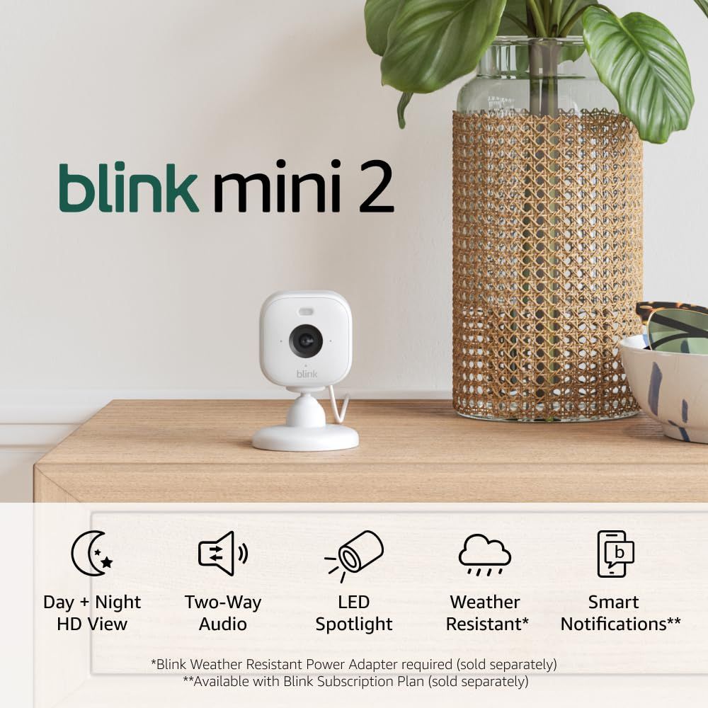 Shows the Blink Mini 2 camera in a real home environment to help shoppers visualize how it fits naturally into their living space. Uses graphic overlays including the product name and feature icons…
