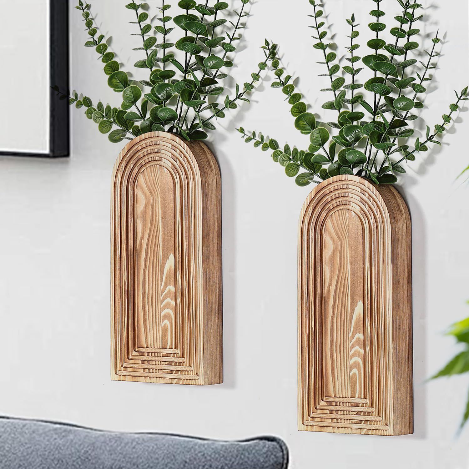 Shows the wooden arch vases styled in a real home environment with greenery to help shoppers visualize how the product will look in their own living space. Displays the core sellable product - a set…