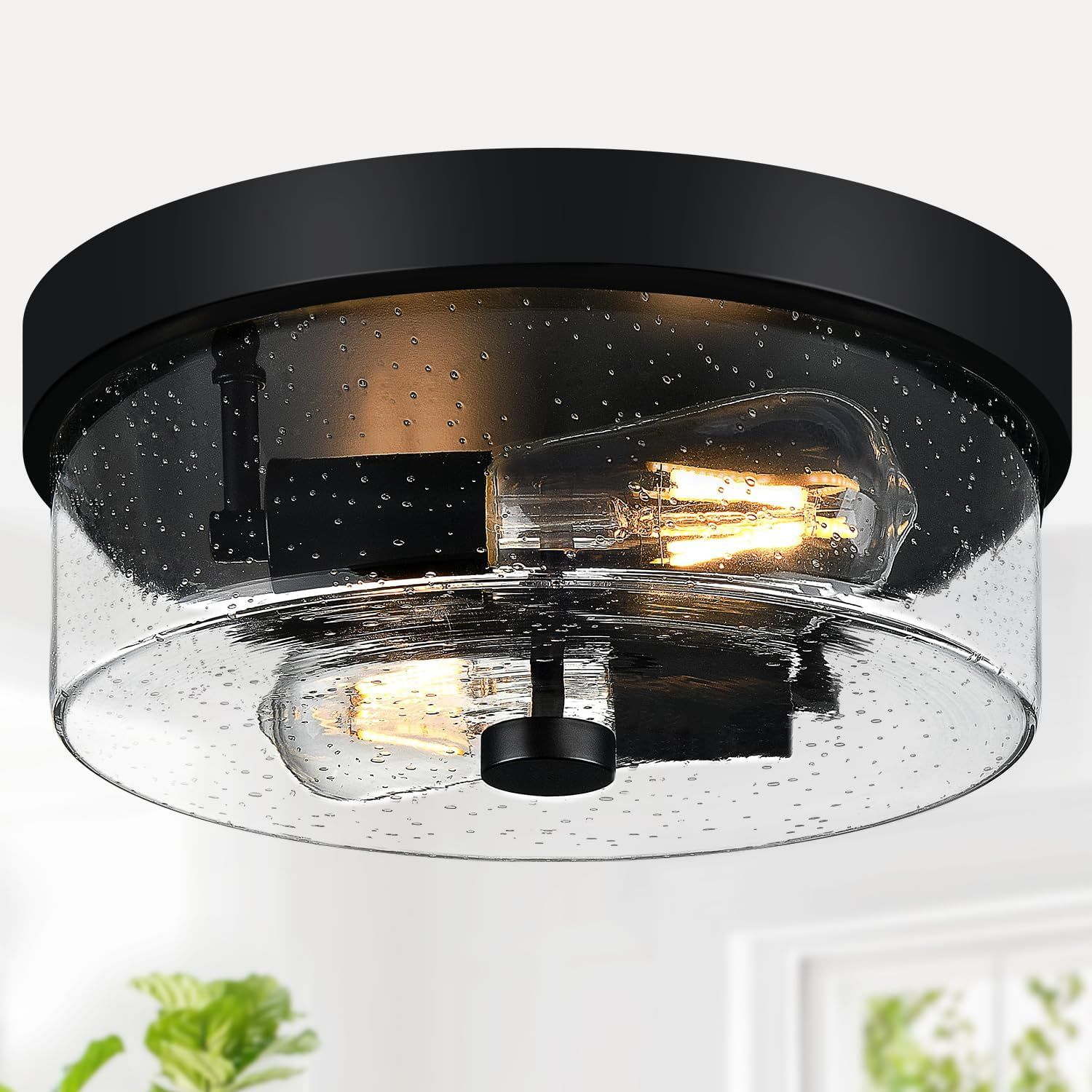 Displays the core product, a flush-mount ceiling light fixture with a seeded glass shade and black finish, to show shoppers exactly what they will receive. Shows the light fixture installed in a…