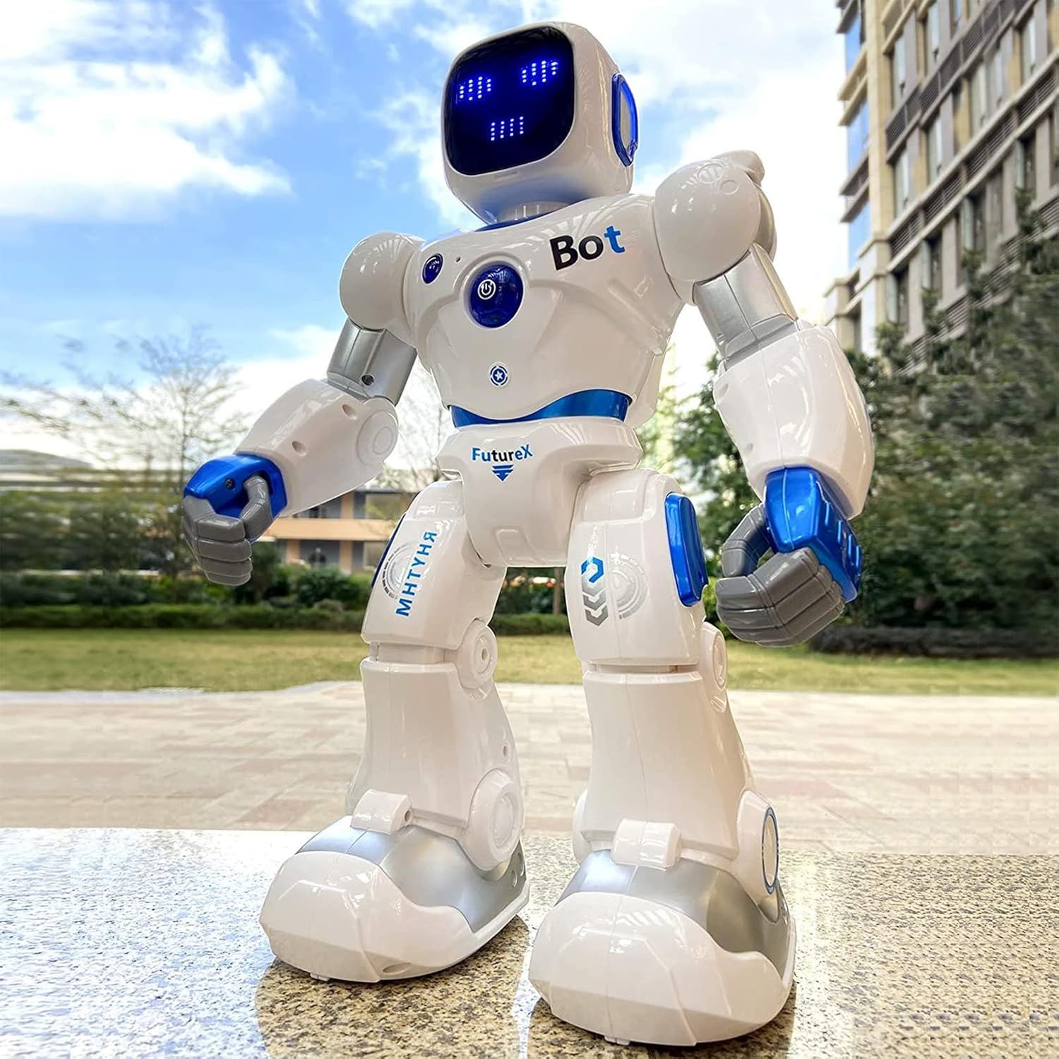Shows the core product—a white and blue robot toy with LED screen face and articulated joints—in an outdoor lifestyle setting to demonstrate its design, features, and appeal as an interactive toy.…