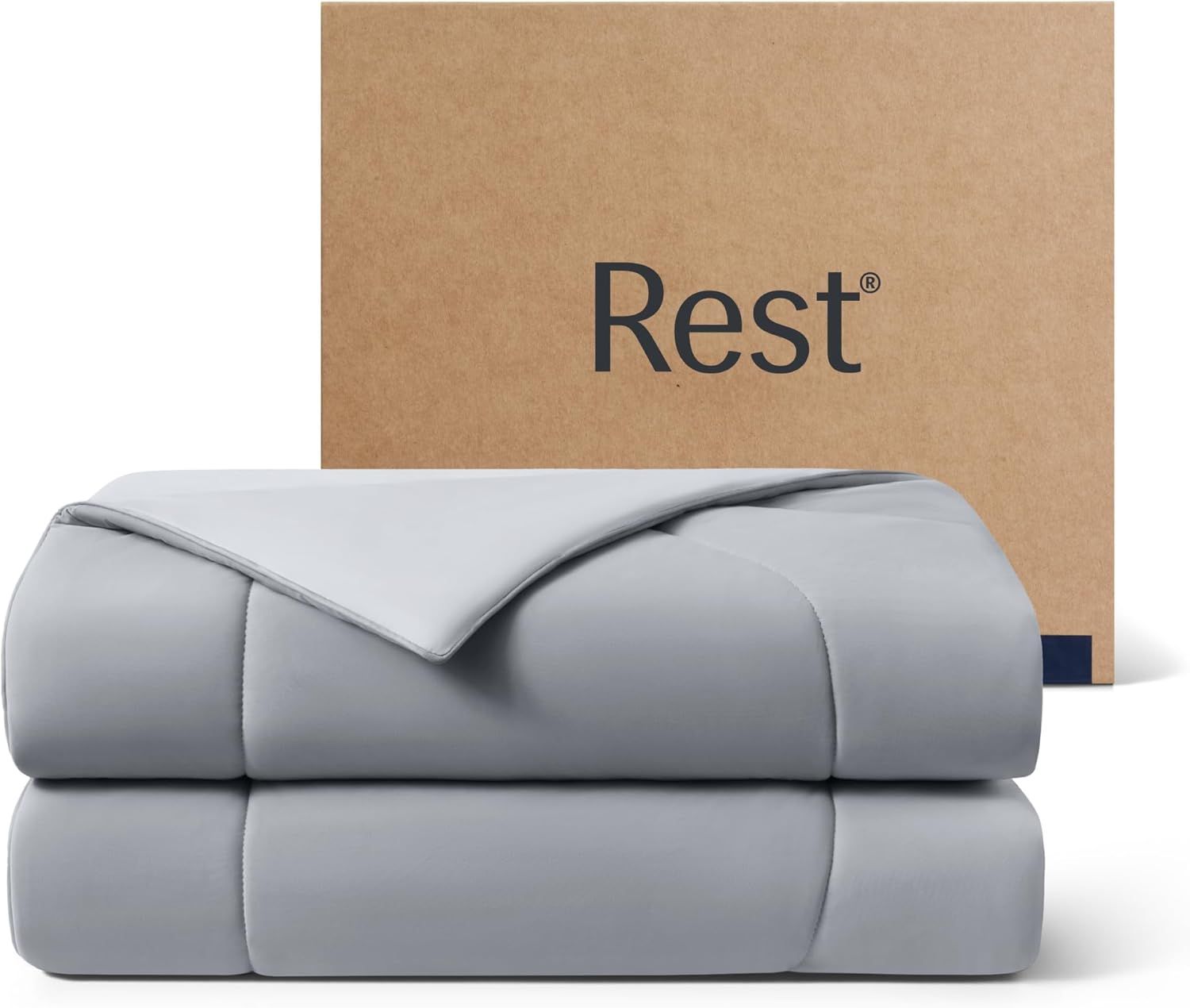 Shows the core product, a neatly folded gray comforter or duvet, to communicate its appearance, color, and quality to the shopper. Displays the Rest-branded cardboard packaging box behind the…
