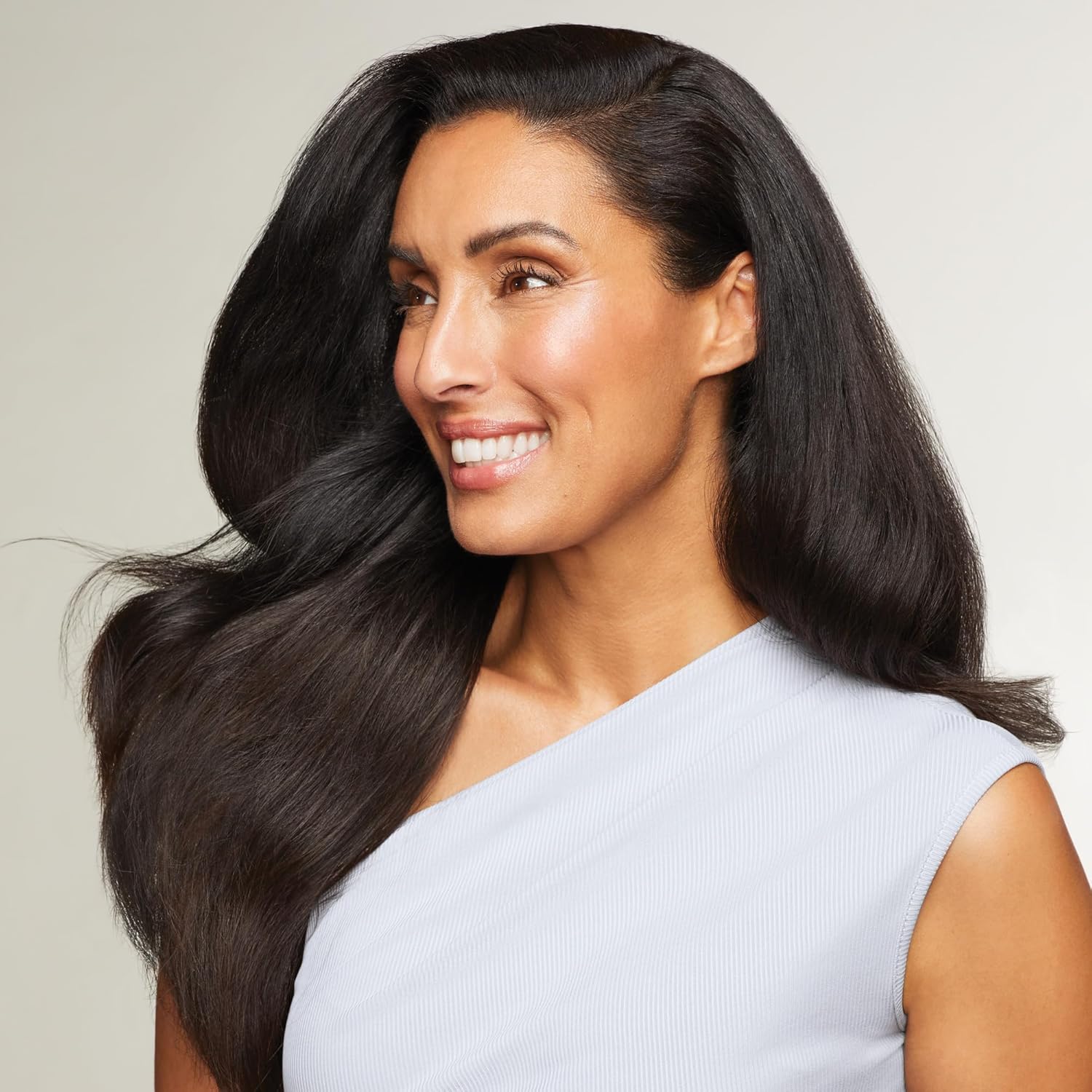 Showcases a real person with a bright smile and shiny hair, likely to demonstrate the results of using a hair care or beauty product.