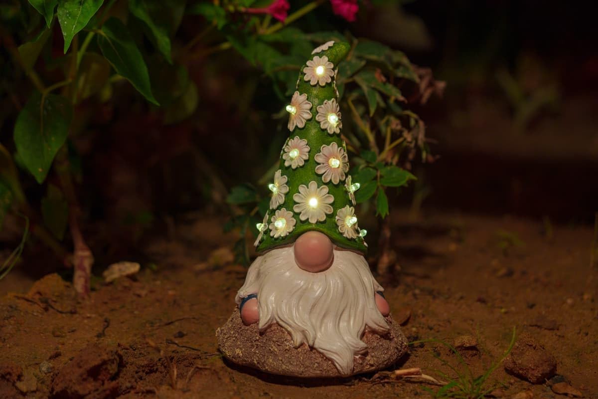 Showcases the product in a natural garden setting to demonstrate its decorative appeal and lighting feature. Highlights the unique illuminated floral hat feature of the gnome, emphasizing its…