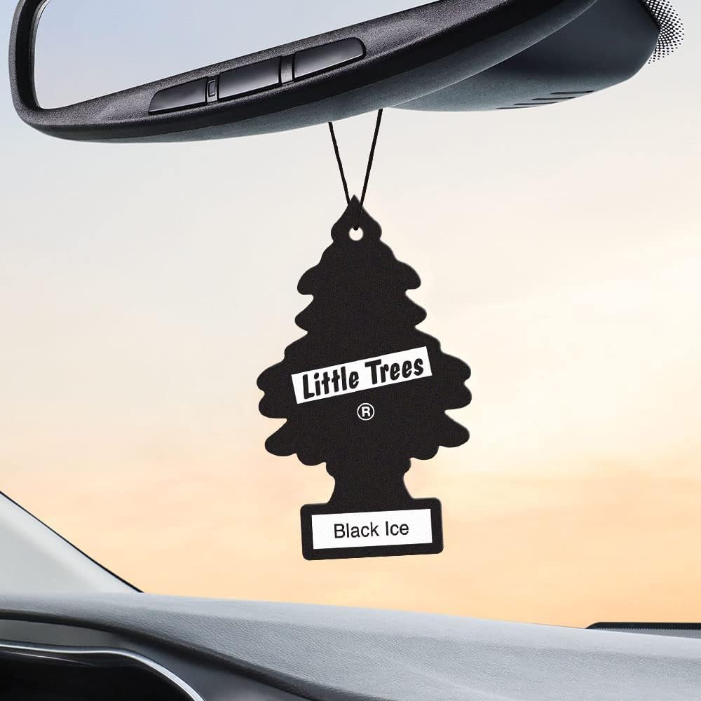 Showcases the Little Trees air freshener product in a realistic car setting to demonstrate its intended use and placement.