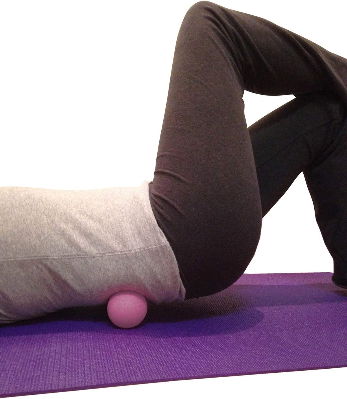 Demonstrates how to use the massage ball for lower back relief, showing proper positioning and technique.