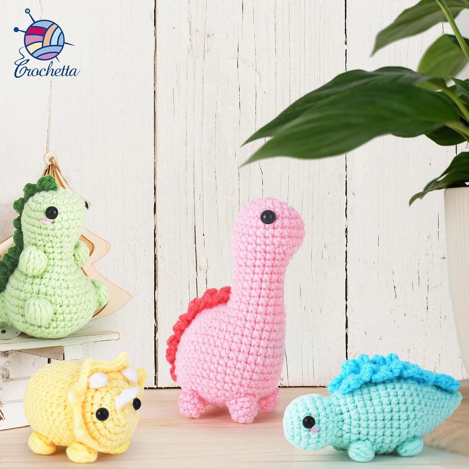 Shows the crocheted dinosaur toys in a styled home environment to help shoppers visualize the products as decorative items or gifts in a real-world context.