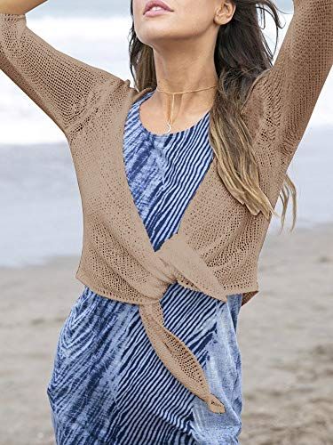 Shows the product being worn in a real-world beach setting to help shoppers visualize how the dress looks when styled casually with a cardigan in an outdoor environment.