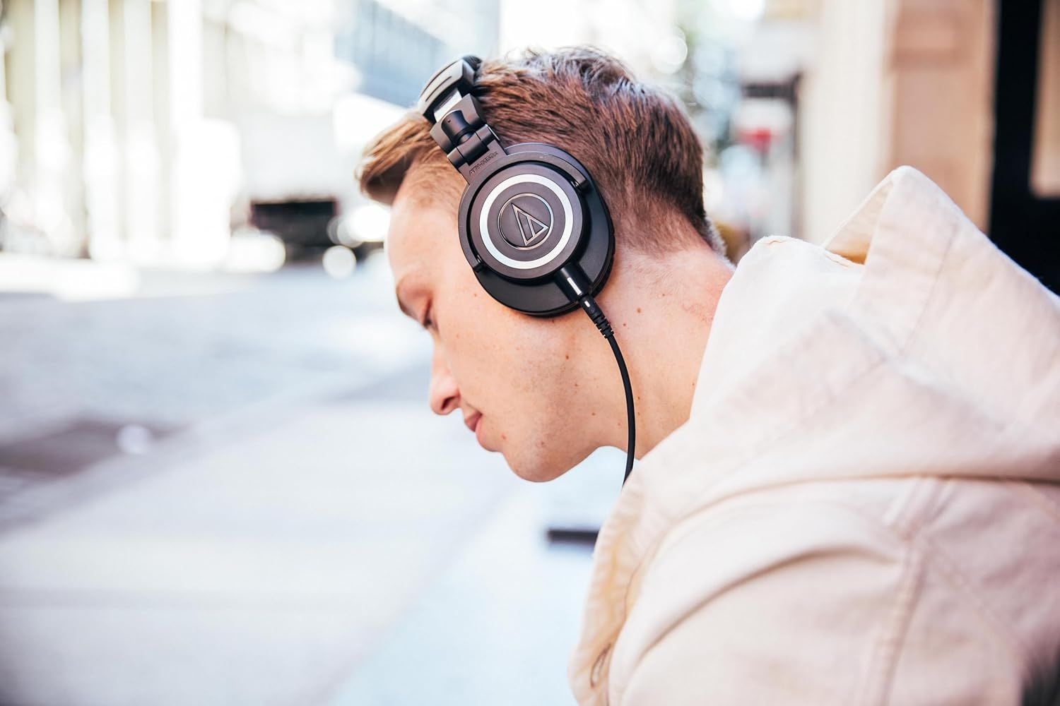 Shows the headphones being worn by a person in a natural outdoor environment to help shoppers visualize how the product looks and fits in everyday use.
