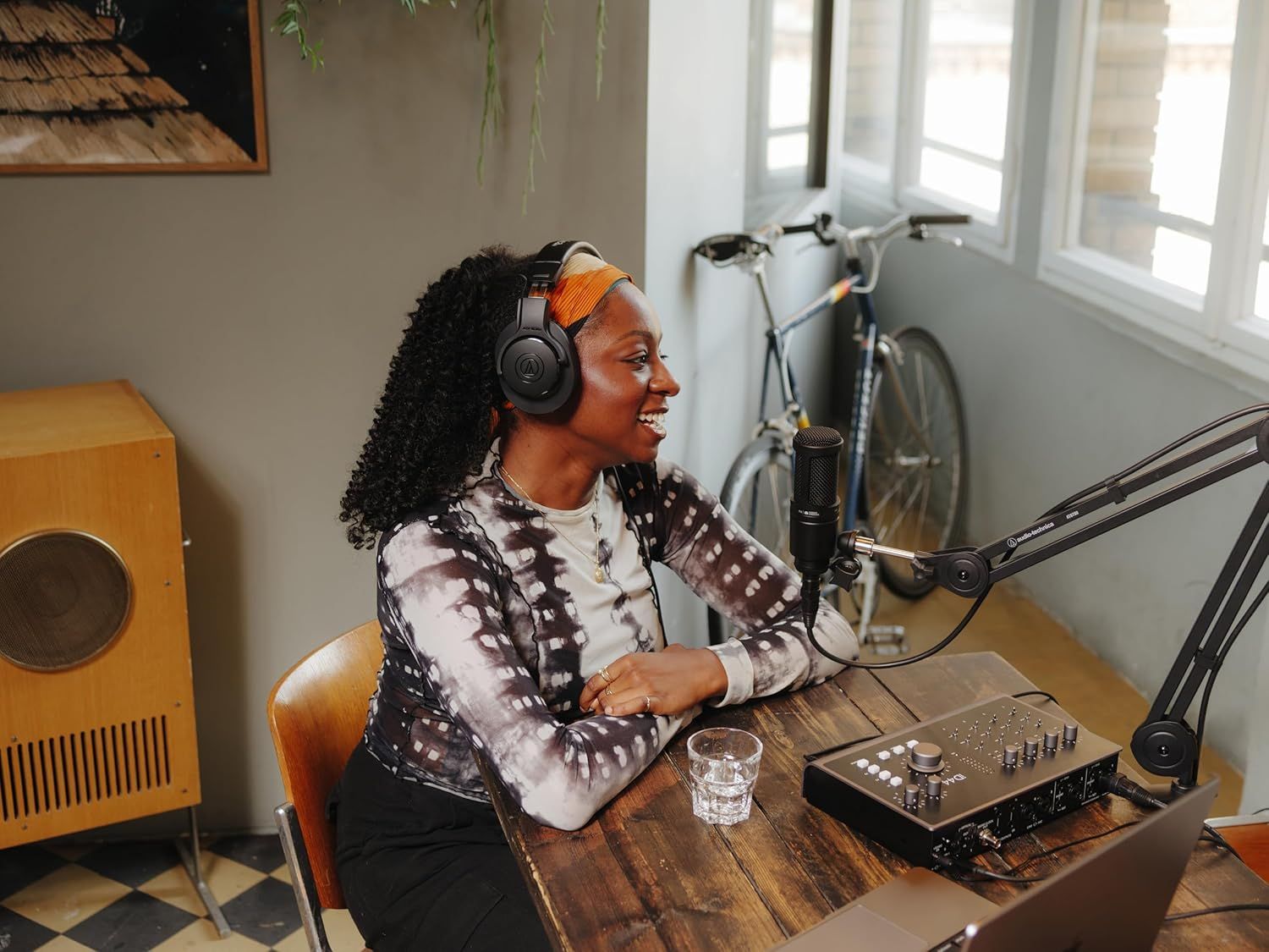 Shows the product being used in a real-world home podcasting environment to help shoppers visualize how the microphone fits into their own creative workspace.