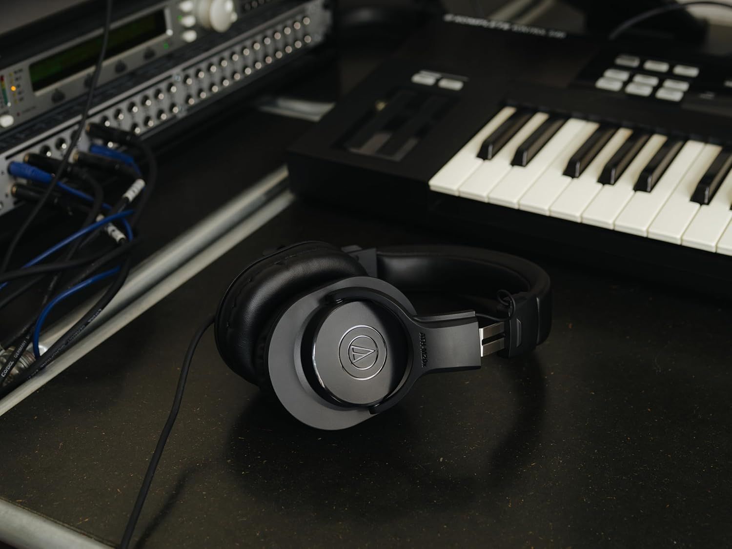 Demonstrates the headphones in a professional music production environment with audio equipment and keyboard to show its application for studio recording and music creation.
