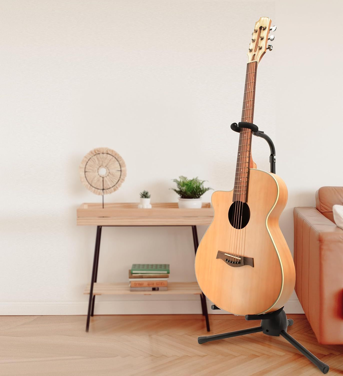 Shows the guitar stand in a real-world home setting to help shoppers visualize how the product looks and fits in their living space.