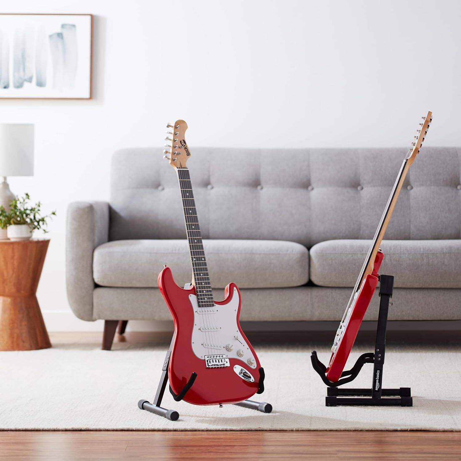 Shows the product in a natural living room environment to help shoppers visualize how the guitar stands would look and fit in their own home space.