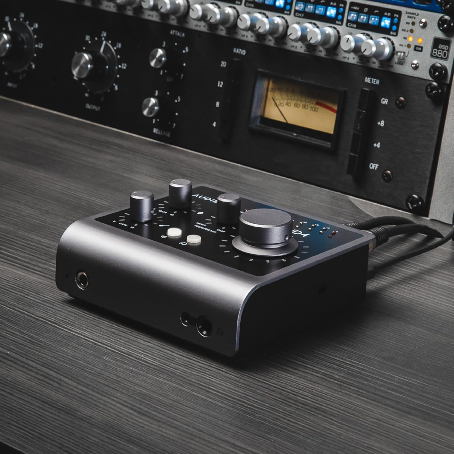 Shows the audio interface in a real-world professional studio setting with high-end equipment to demonstrate its intended use case and target audience.