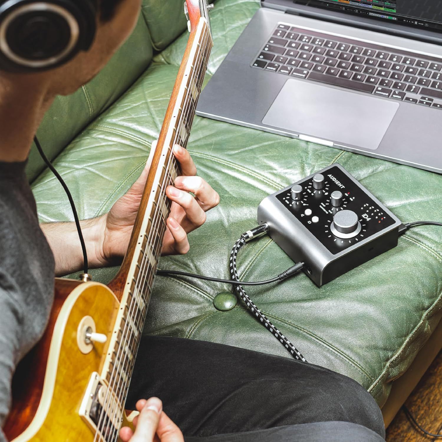 Shows the product being used in a real-world home music recording environment to help shoppers visualize how the audio interface fits into their creative workflow.