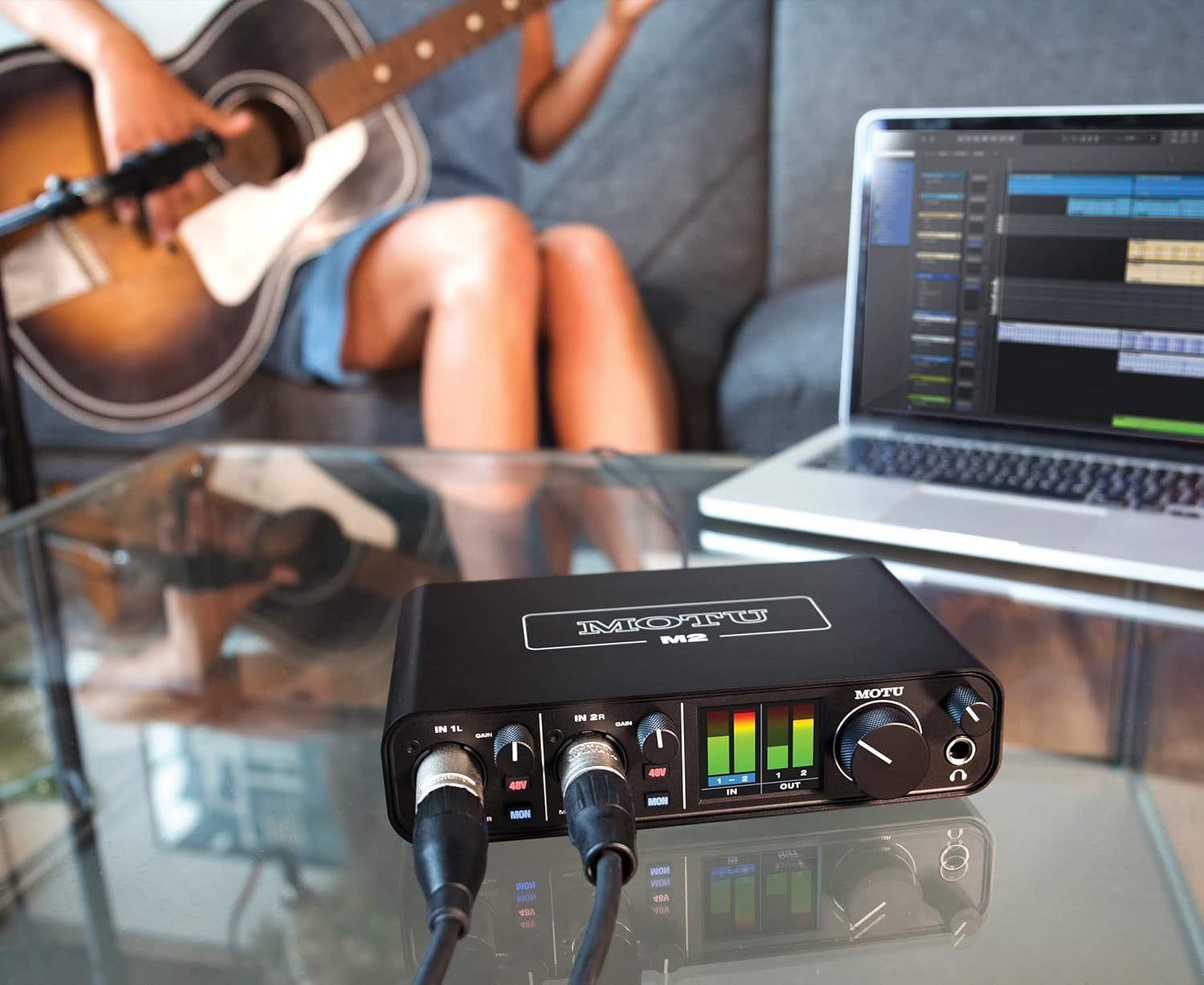 Demonstrates the audio interface being used in a real-world music recording scenario with guitar and laptop, showing its versatility for musicians and content creators.