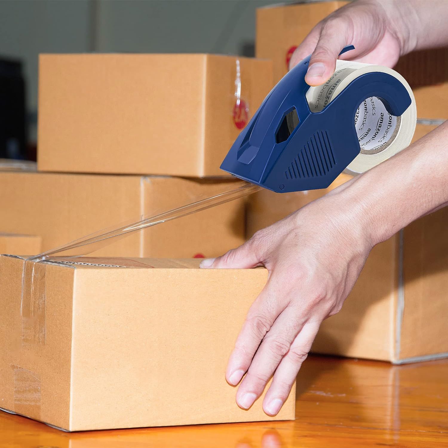 Shows the tape dispenser being used in a real-world packing scenario to help shoppers visualize the product in action.