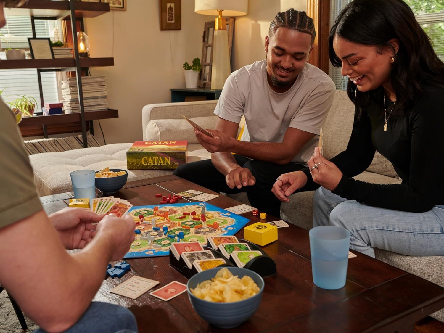 Demonstrates the product being enjoyed in a real-world home setting with friends or family, creating an emotional connection and showing the social, fun nature of the board game.