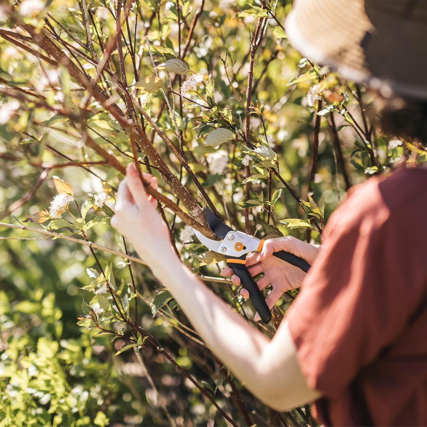 Demonstrates the product being used in a real-world gardening context to help shoppers visualize themselves using the pruning shears outdoors.