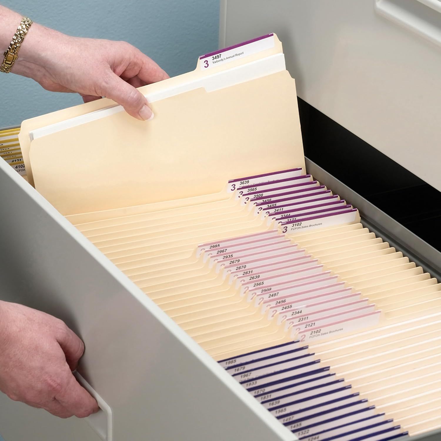 Demonstrates the product in a real-world office setting, showing how the filing system organizes documents in a drawer with hands interacting naturally with the folders.