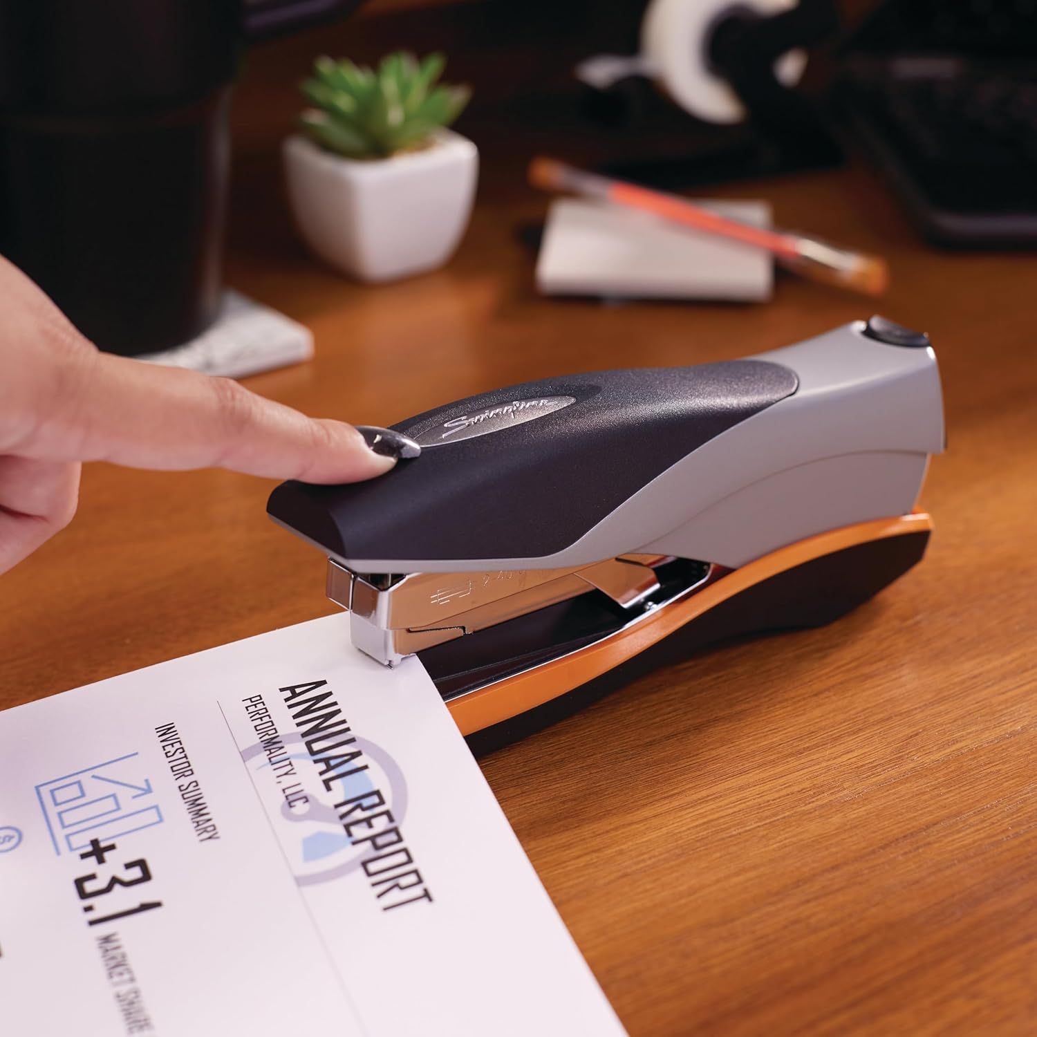 Demonstrates the product in a real-world office setting to help shoppers visualize the stapler in everyday use on their desk.