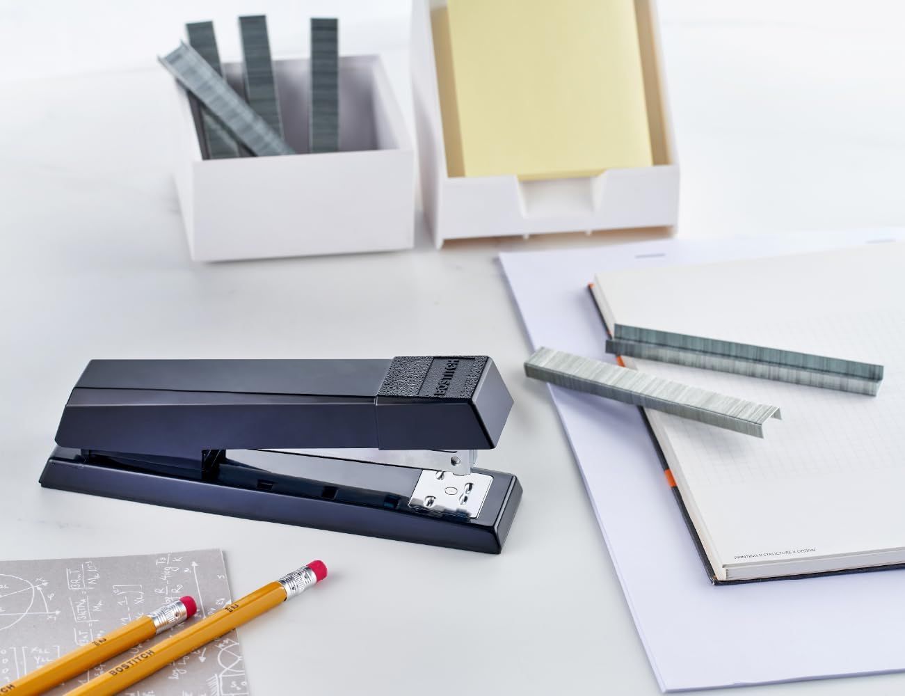 Shows all the items included with the stapler purchase, including the stapler, staples, notepads, and pencils, to communicate the complete value of the bundle.