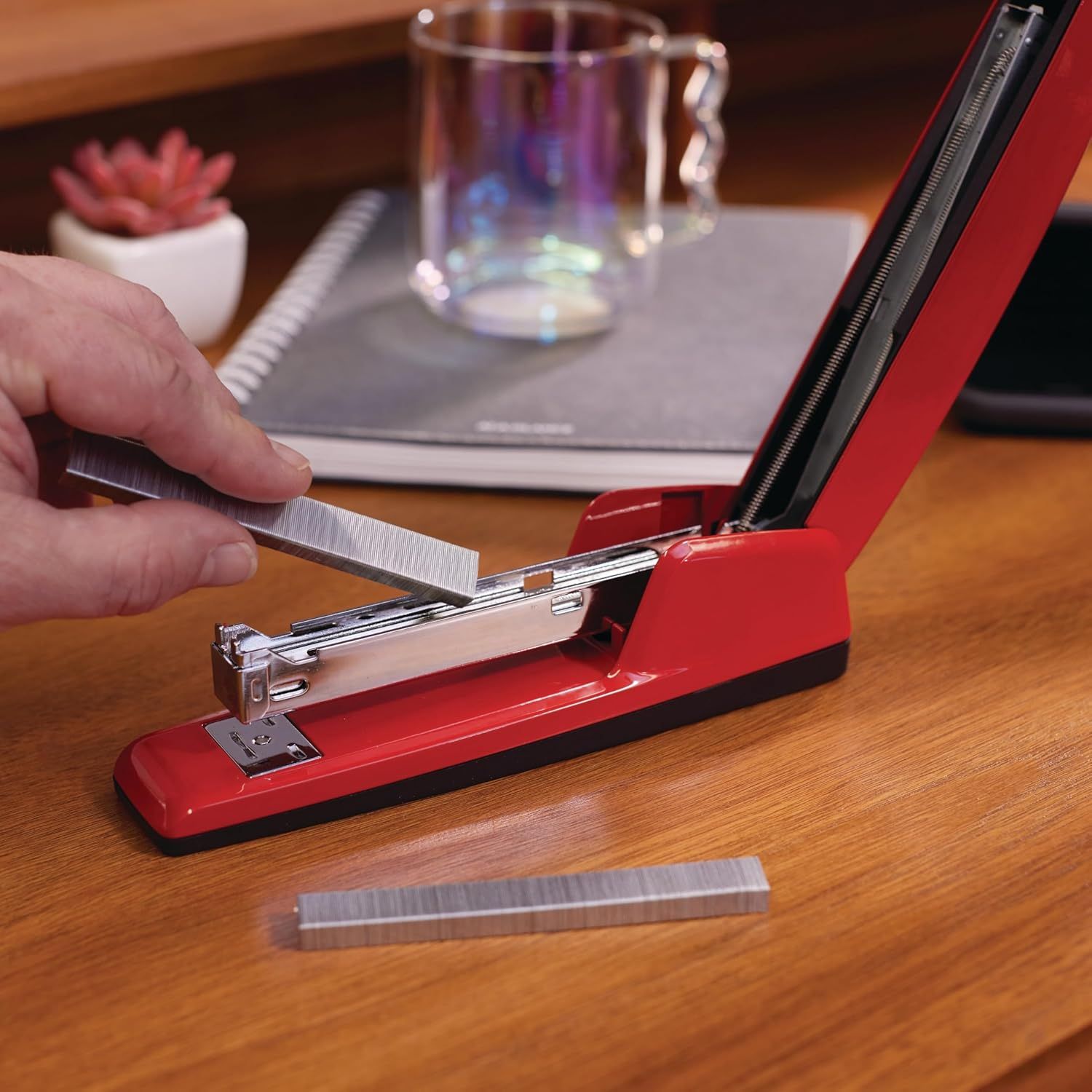 Demonstrates the product in a real-world office or home setting to help shoppers visualize how the stapler fits naturally into their workspace.