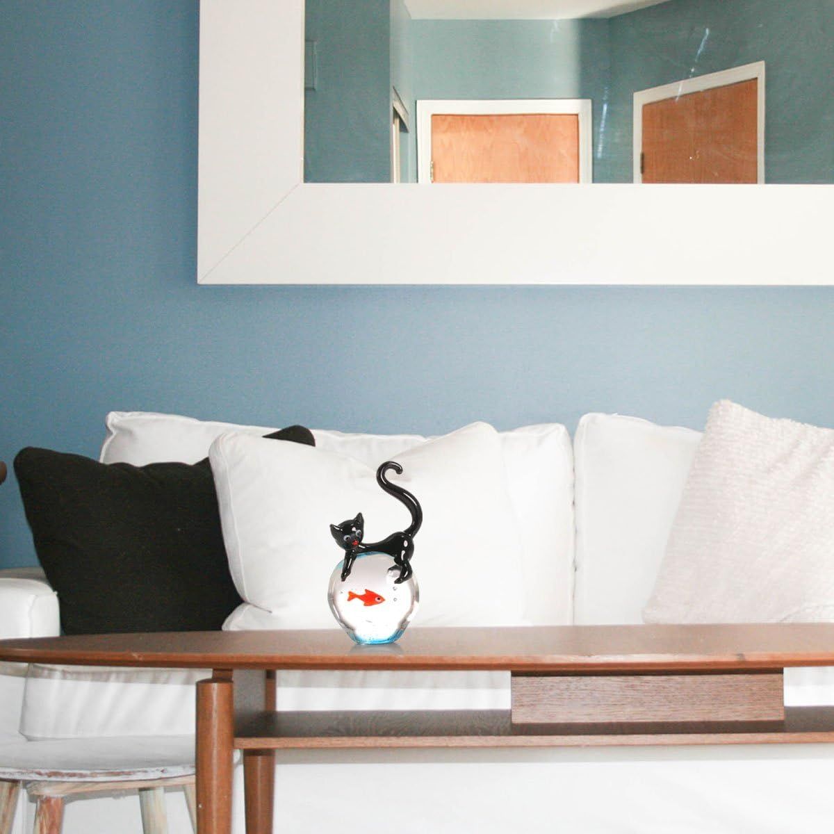 Showcases the product (decorative cat and fishbowl figurine) in a real-world living room environment to help shoppers visualize how it would look in their own home.