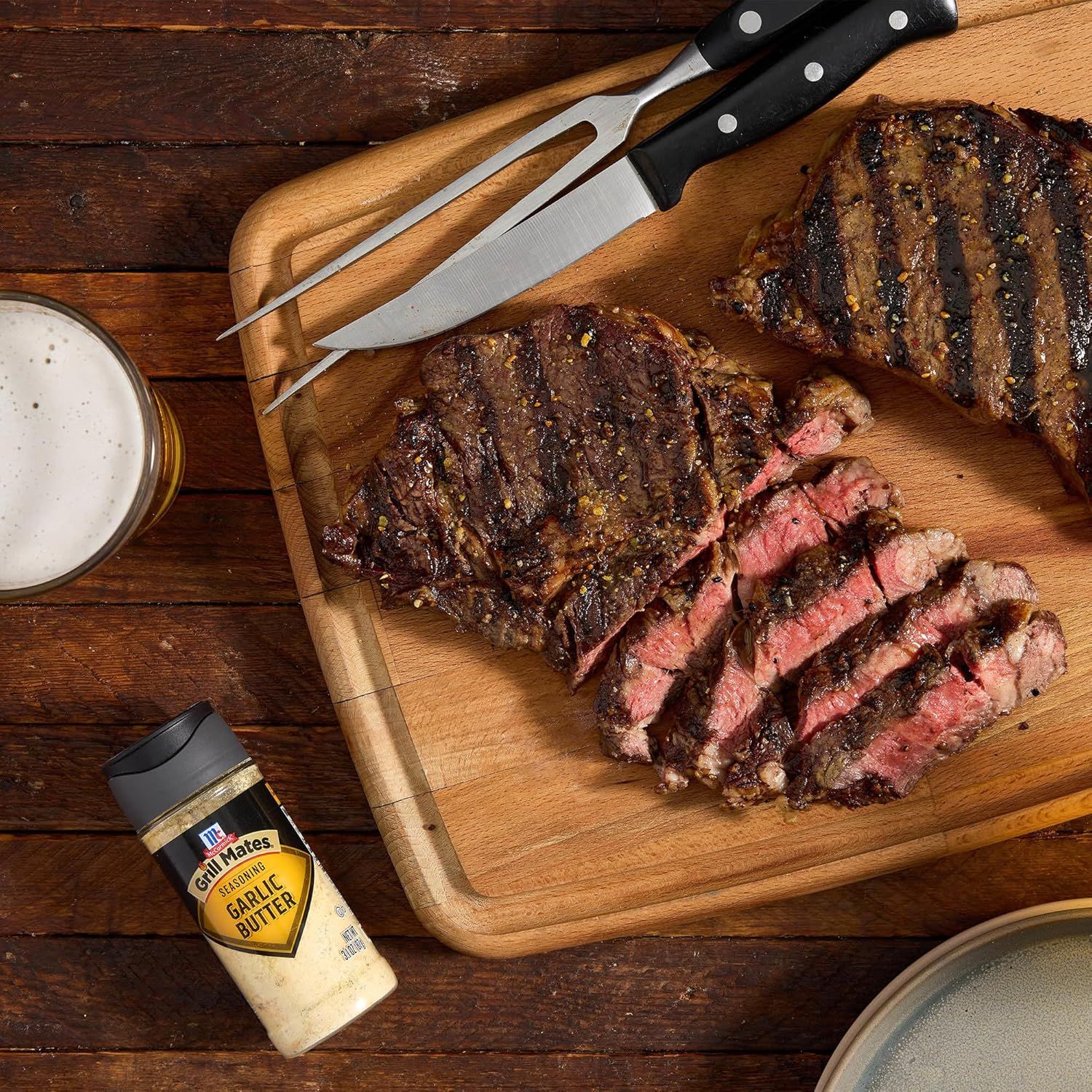 Showcases the product (garlic butter seasoning) in a real-world culinary context with grilled steaks to help shoppers visualize how they would use it and the appetizing results it delivers.