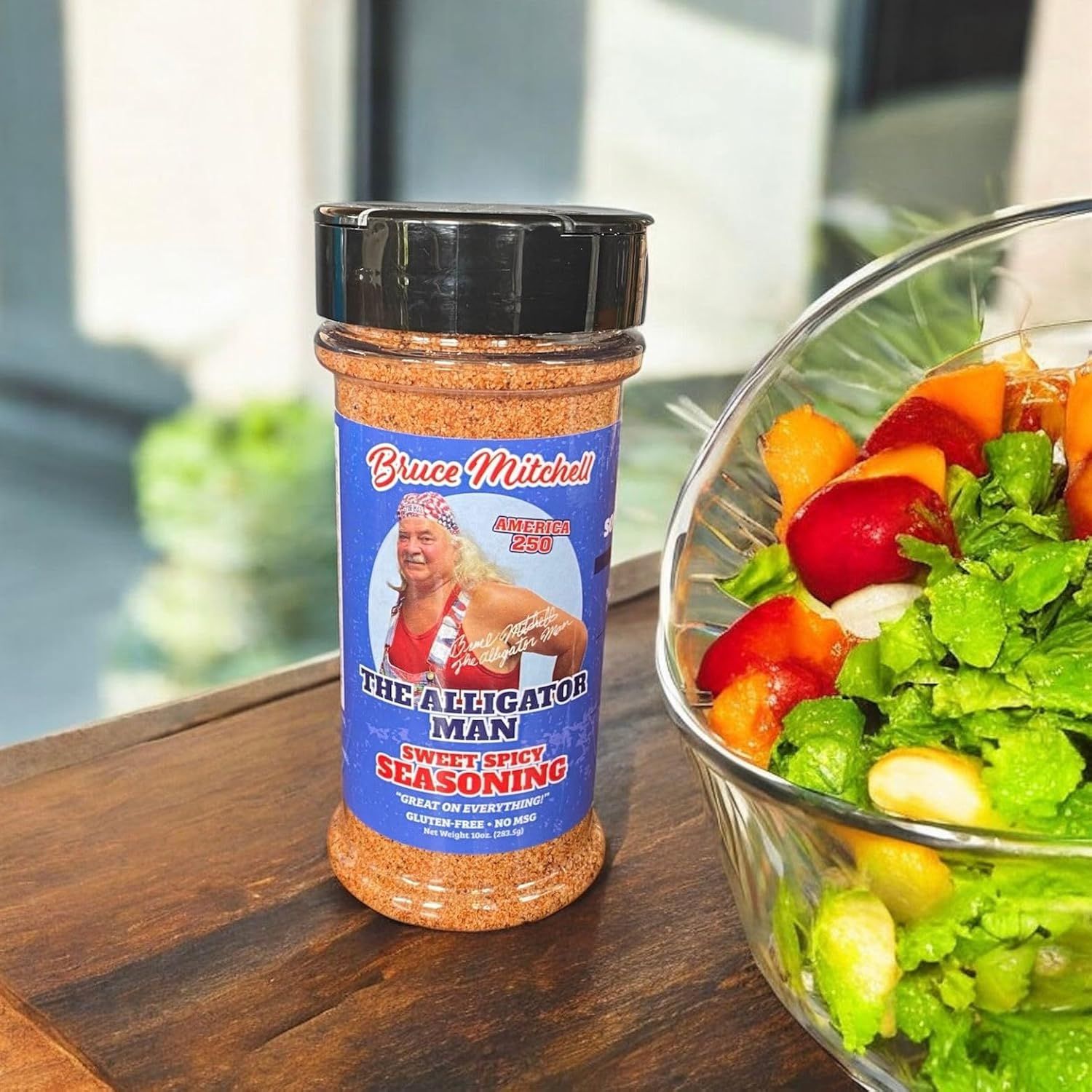 Shows the seasoning product in an authentic home kitchen setting with a fresh salad, demonstrating natural everyday use without any text overlays or callouts.