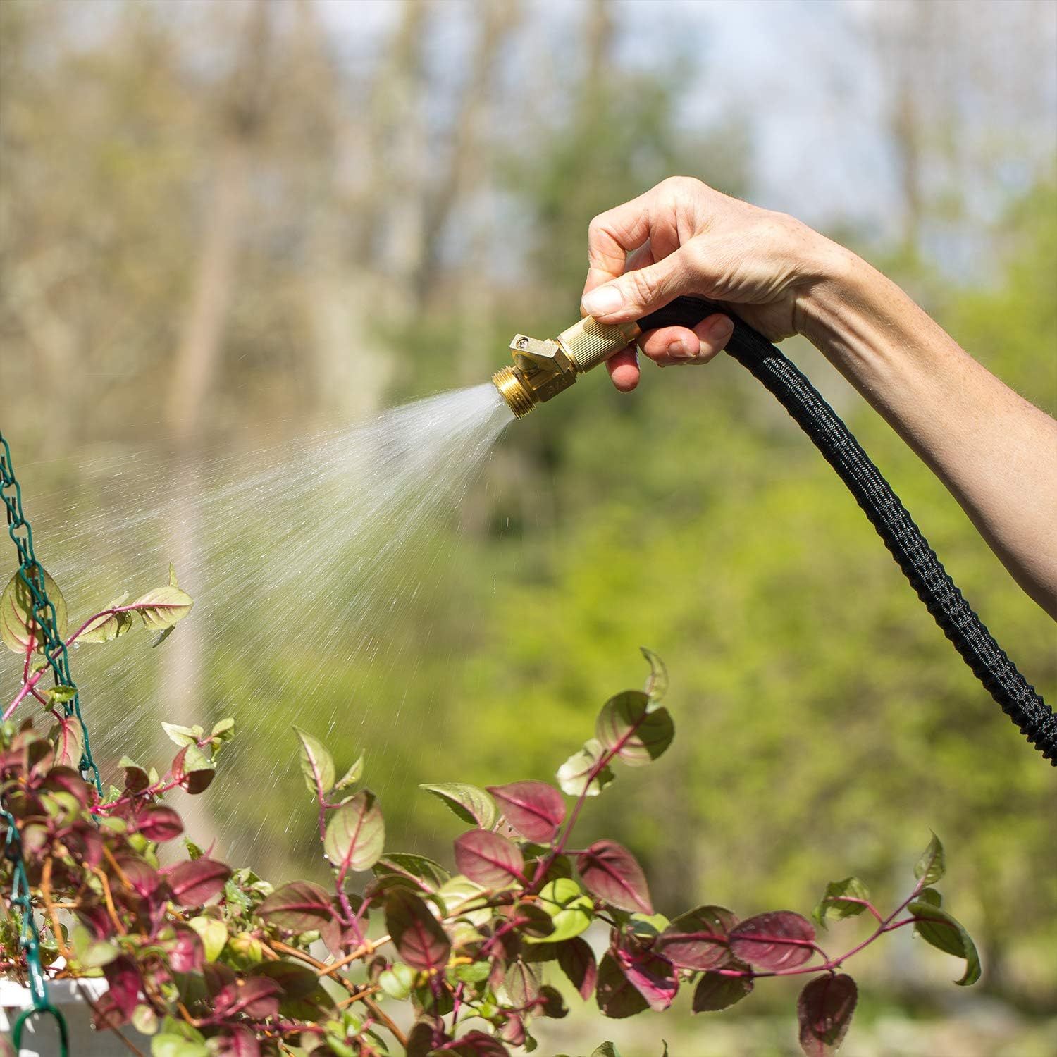 Demonstrates the product in a real-world gardening context to help shoppers visualize using the hose nozzle for watering plants outdoors.