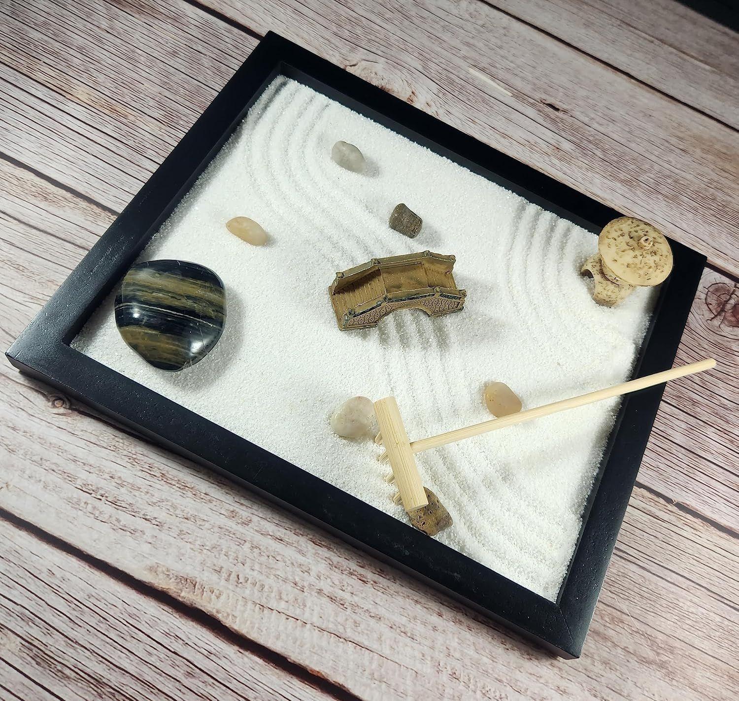 Shows all the components included with the product—sand, stones, rake, and decorative elements—to help shoppers understand the complete kit they will receive.