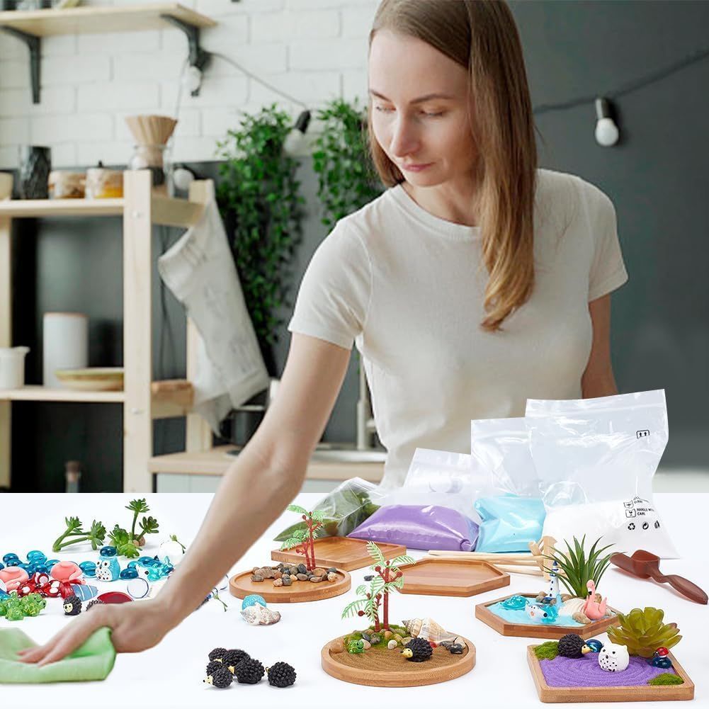 Shows everything included in the kit—wooden trays, colored sand, decorative elements, plants, and accessories—to help shoppers understand the complete value and contents they'll receive.