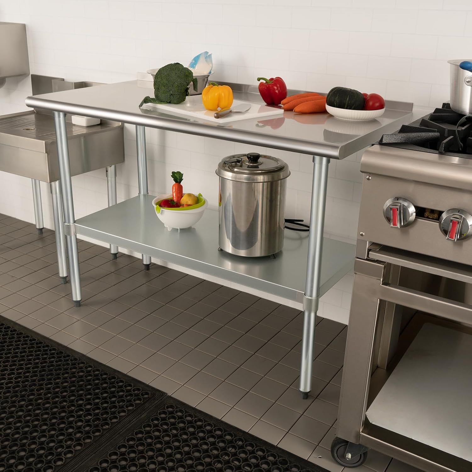 Demonstrates the product (stainless steel work table) in a real-world commercial kitchen environment to help shoppers visualize how it fits into their workspace.