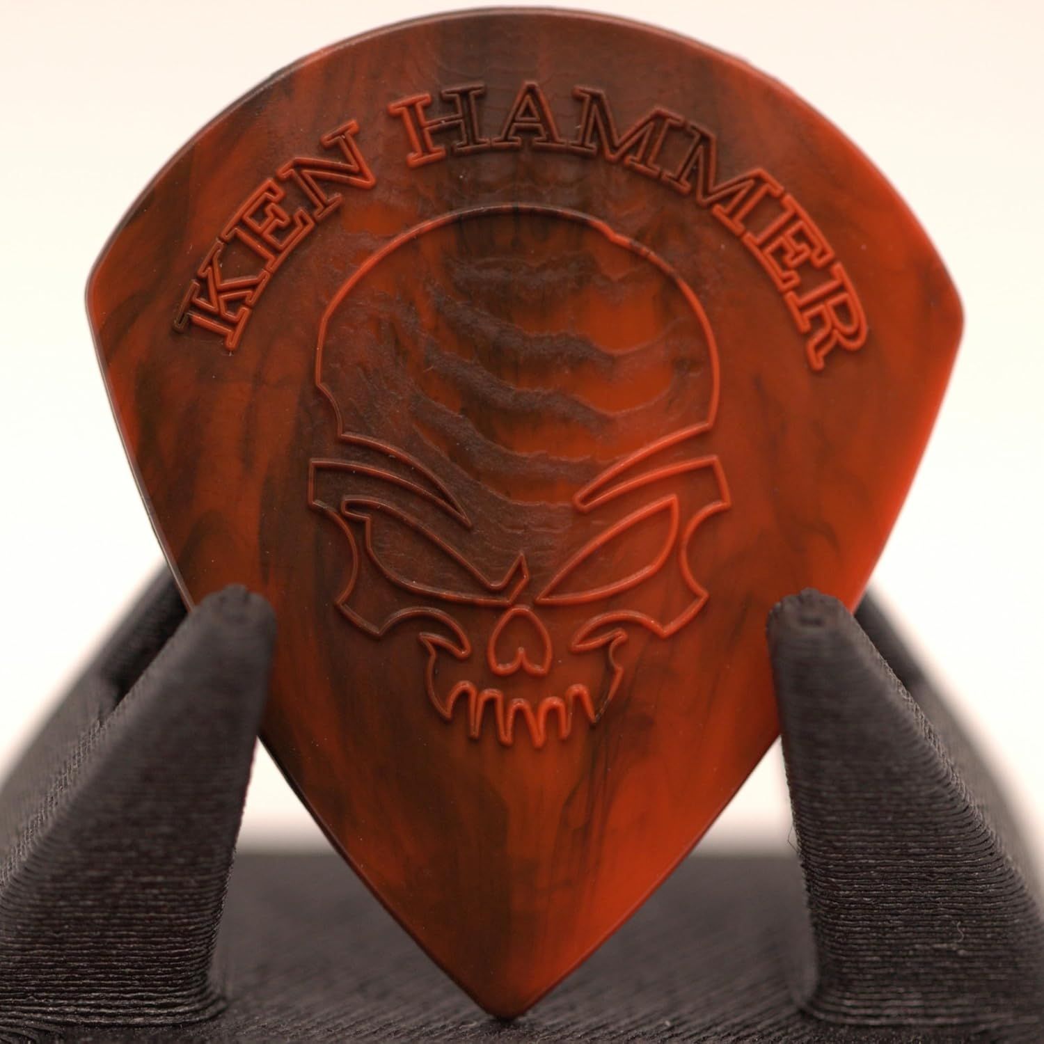 Showcases the Ken Hammer brand logo embossed on the guitar pick to establish brand identity and reinforce brand recognition with shoppers.