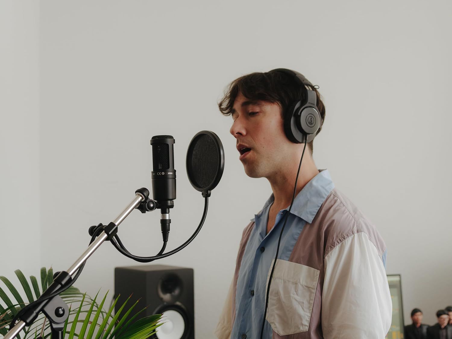 Demonstrates the product being used in a real-world recording or podcasting environment to help shoppers visualize themselves using the microphone and headphones setup.
