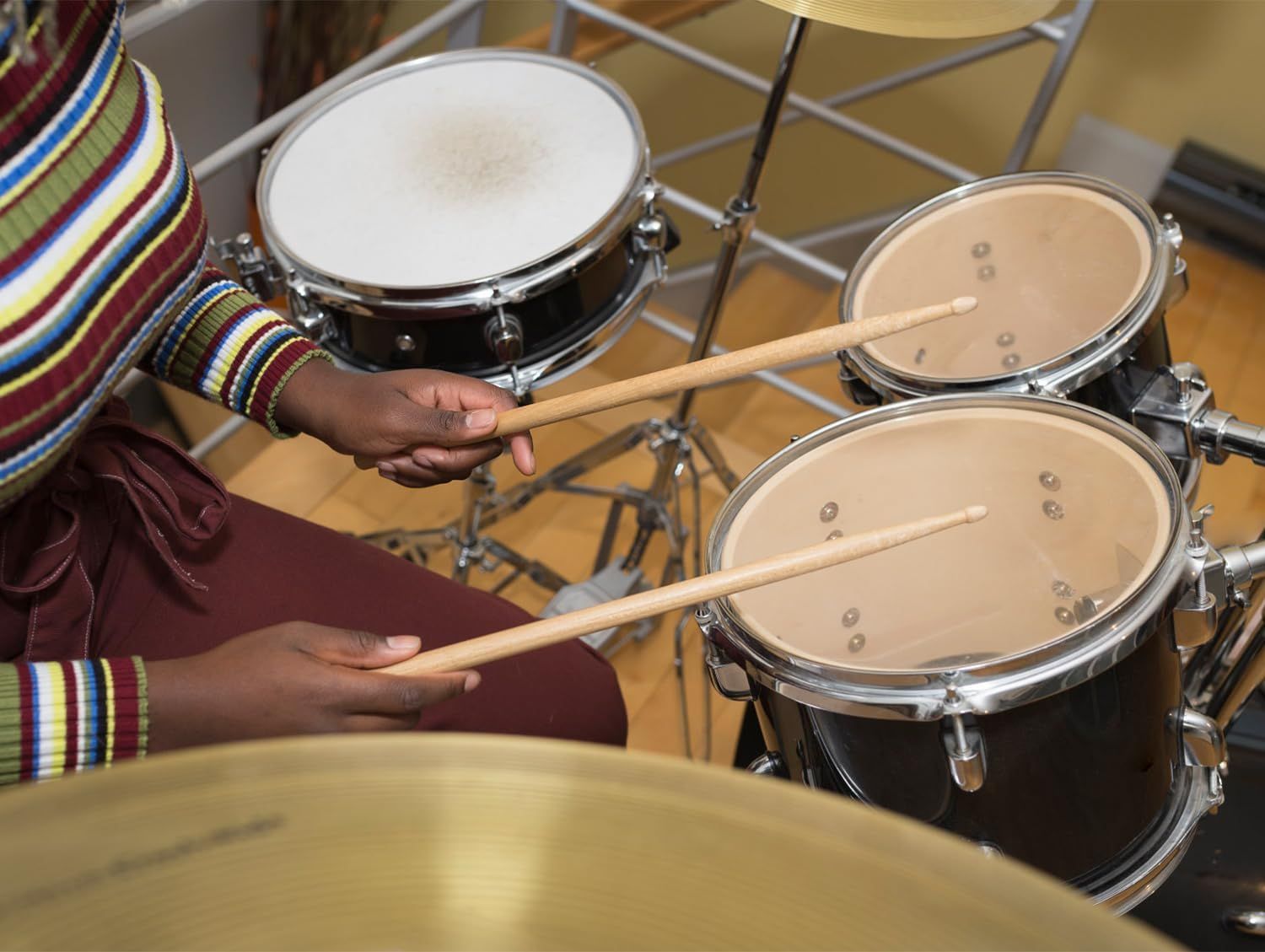 Shows the drum set being played in a real-world context to help shoppers visualize the product in action and understand its practical application.