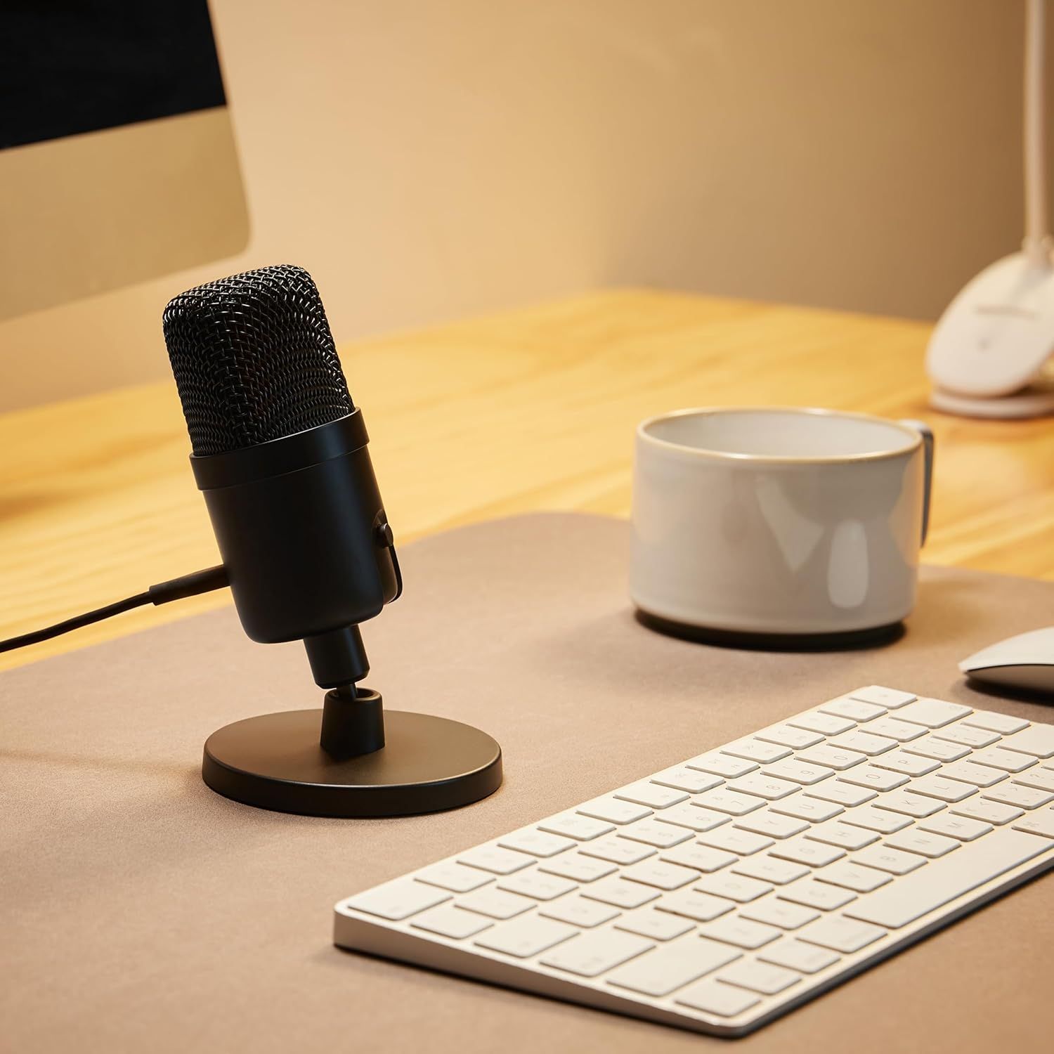 Demonstrates the product in a real-world home office or workspace environment to help shoppers visualize how the microphone fits naturally into their daily work or content creation setup.