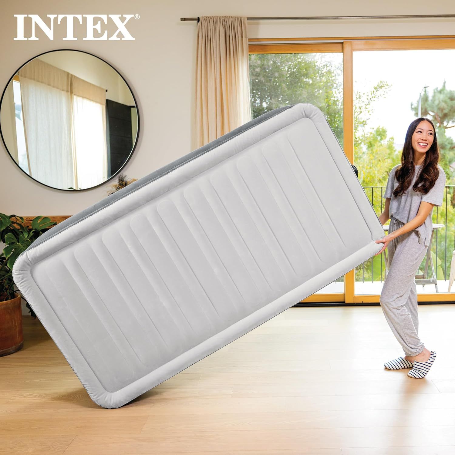 Demonstrates the product in a real-world home setting, showing a person effortlessly handling the air mattress to convey its lightweight and user-friendly nature.