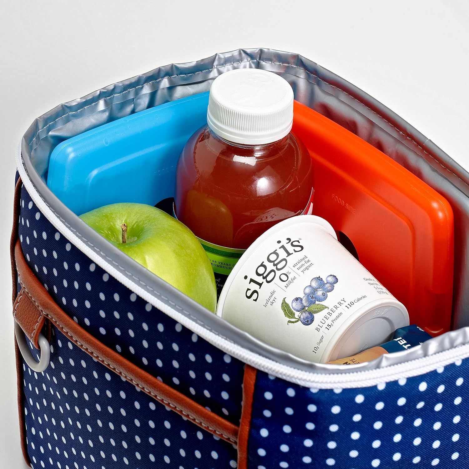 Demonstrates the product in a real-world context showing how it can be used to carry lunch items including drinks, snacks, and fresh fruit, helping shoppers visualize practical everyday use.