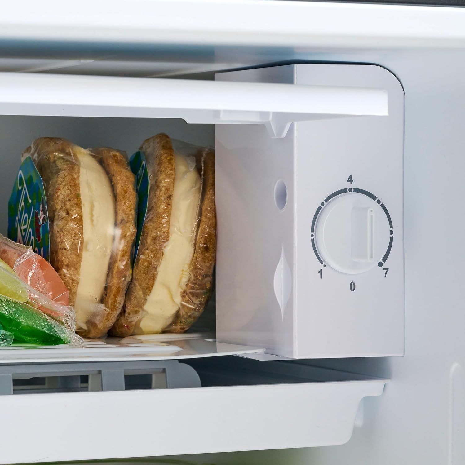 Shows the product in a real-world refrigerator/freezer setting with food items to demonstrate practical everyday use and storage capacity.