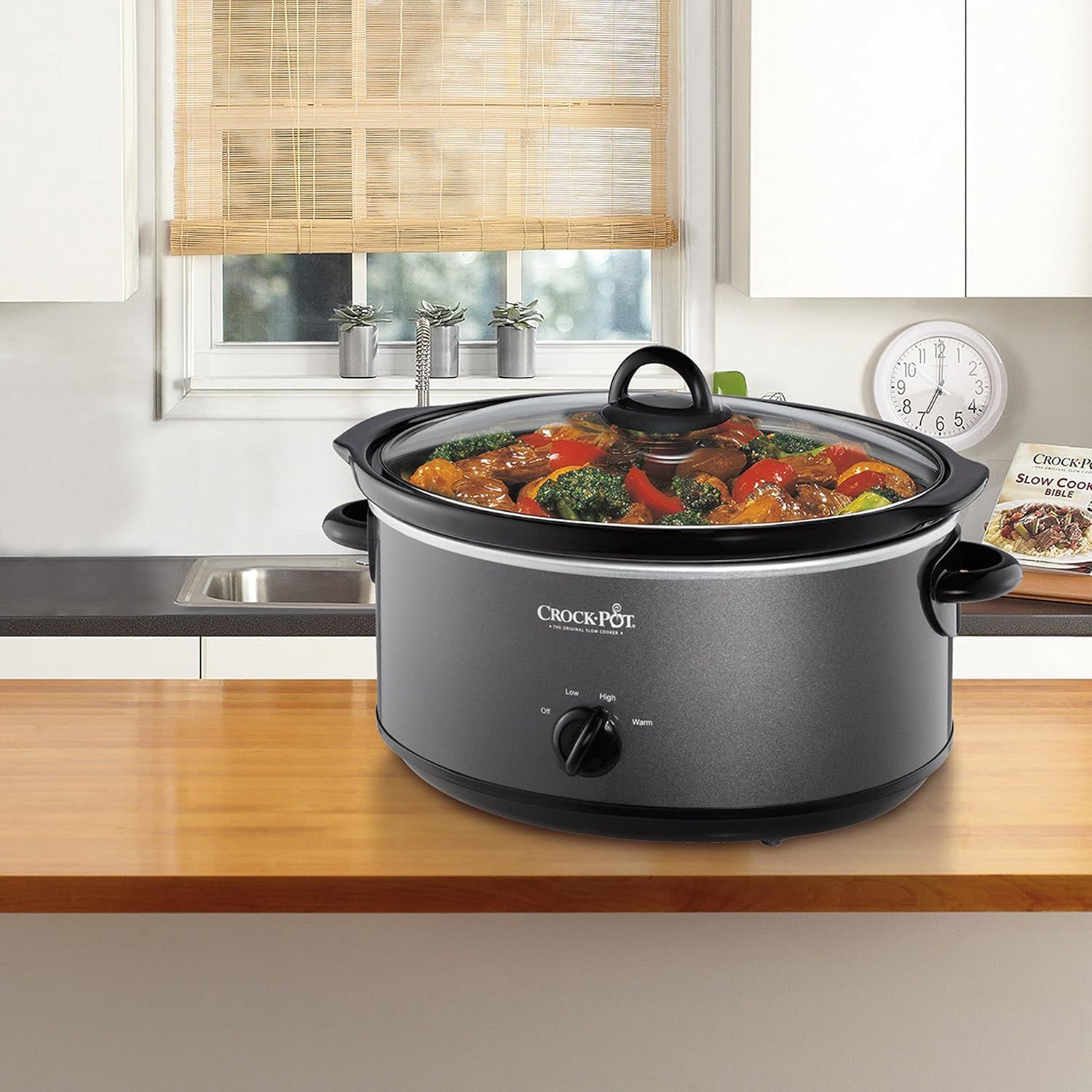 Shows the Crock-Pot slow cooker in a real kitchen environment with prepared food inside, helping shoppers visualize the product in their own home and see the type of meals it can create.