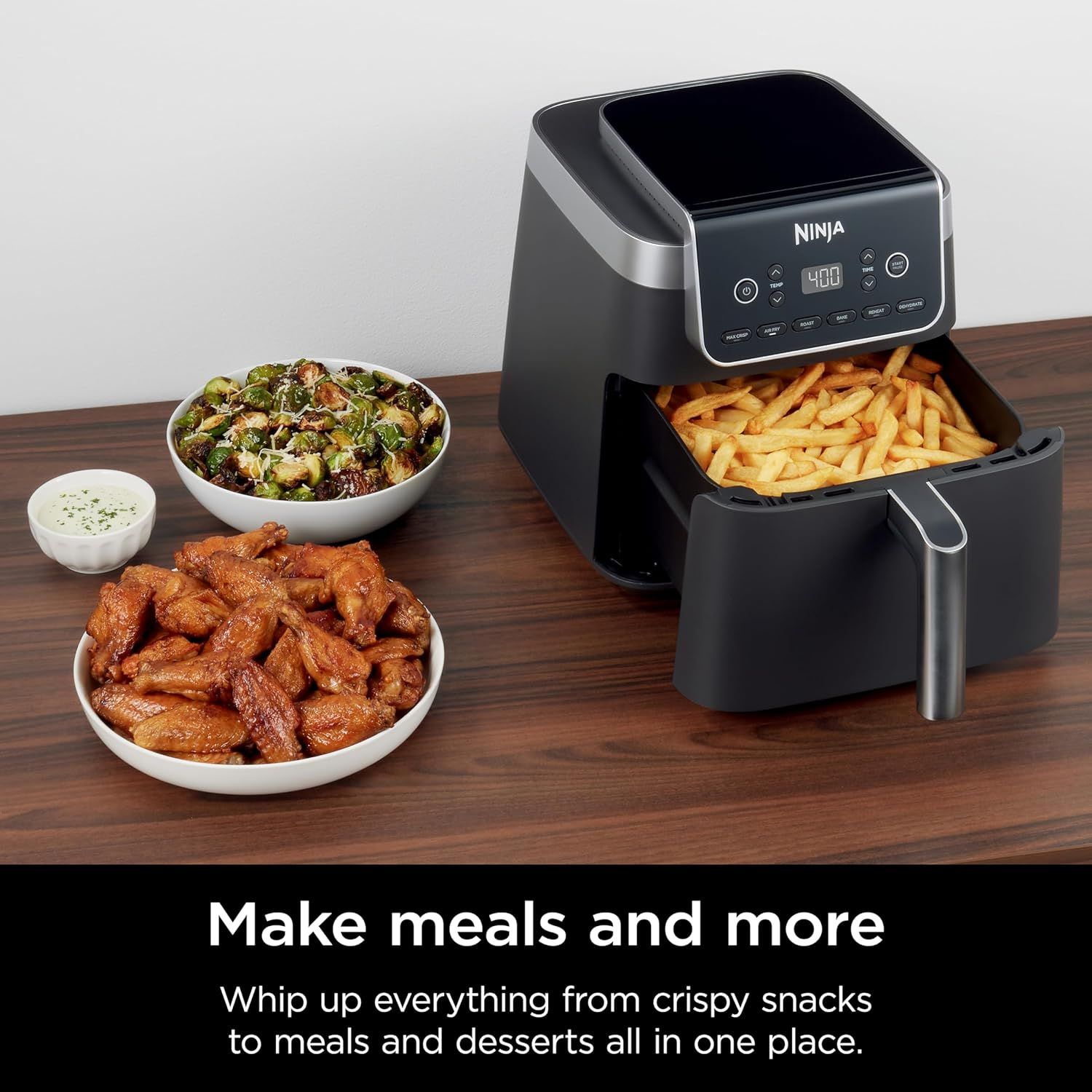 Demonstrates the air fryer's versatility by showing it can prepare multiple types of food (fries, chicken wings, Brussels sprouts) to reassure shoppers of its wide range of cooking applications.…