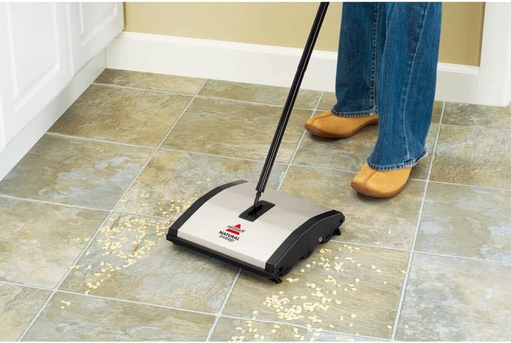 Shows the product being used in a real home environment to help shoppers visualize how the sweeper works on tile floors with debris, demonstrating its practical application.