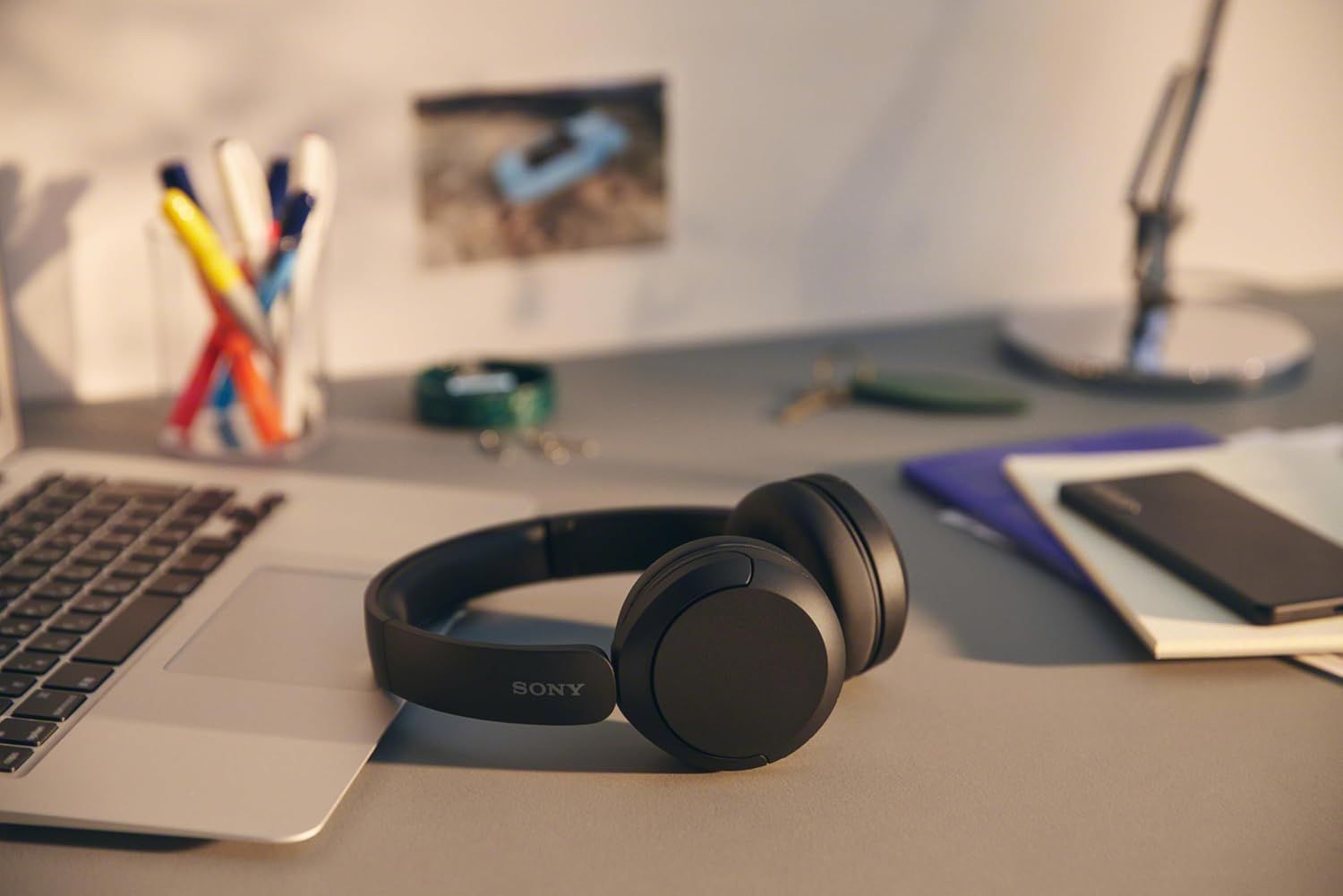 Demonstrates the product in a natural work environment to help shoppers visualize how the headphones fit into their daily lifestyle and workspace.