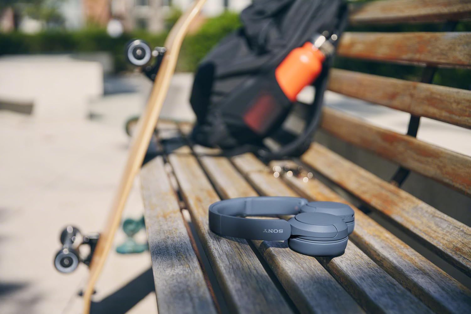 Demonstrates the product in a real-world outdoor lifestyle context, showing its portability and suitability for active, on-the-go use with skateboarding gear.