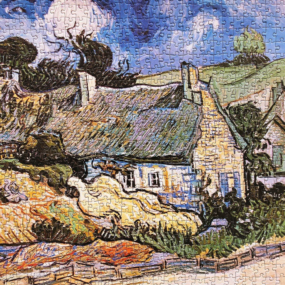 This image shows a completed jigsaw puzzle depicting a cottage with trees and landscape. It appears to be a product display showing the finished puzzle result.